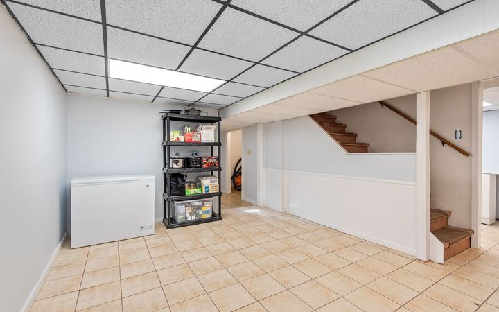 Basement with a suspended tile ceiling and a stair at the back
