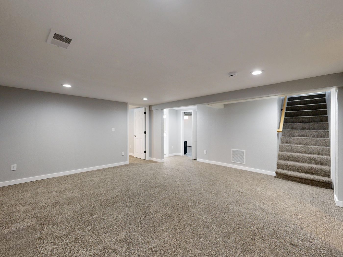 Finished basement with smooth painted drywall and a staircase