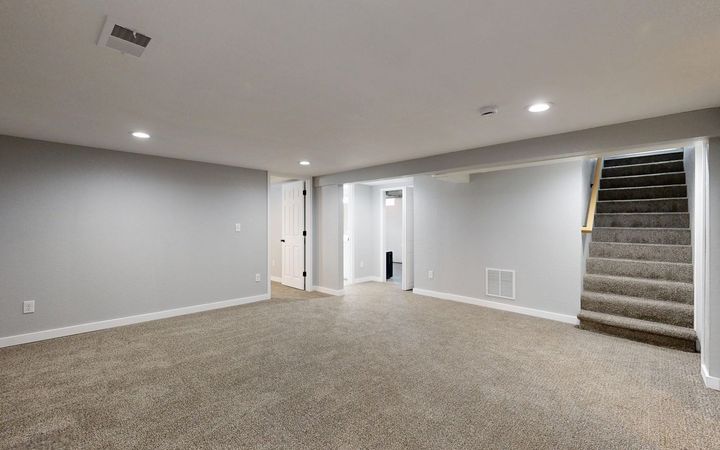 Finished basement with smooth painted drywall and a staircase