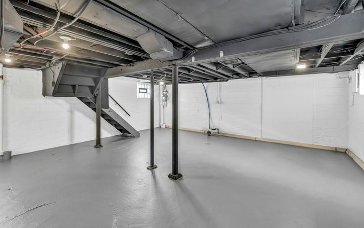 Unfinished basement with bare walls, steel posts and open joists