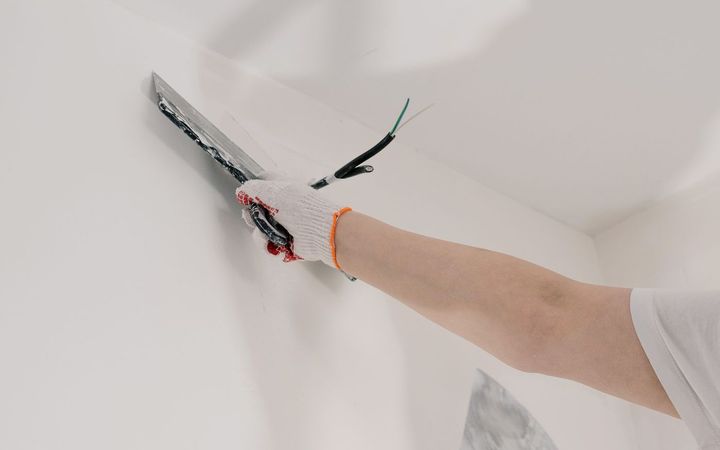 Gloved hand working compound into a crack with a putty knife