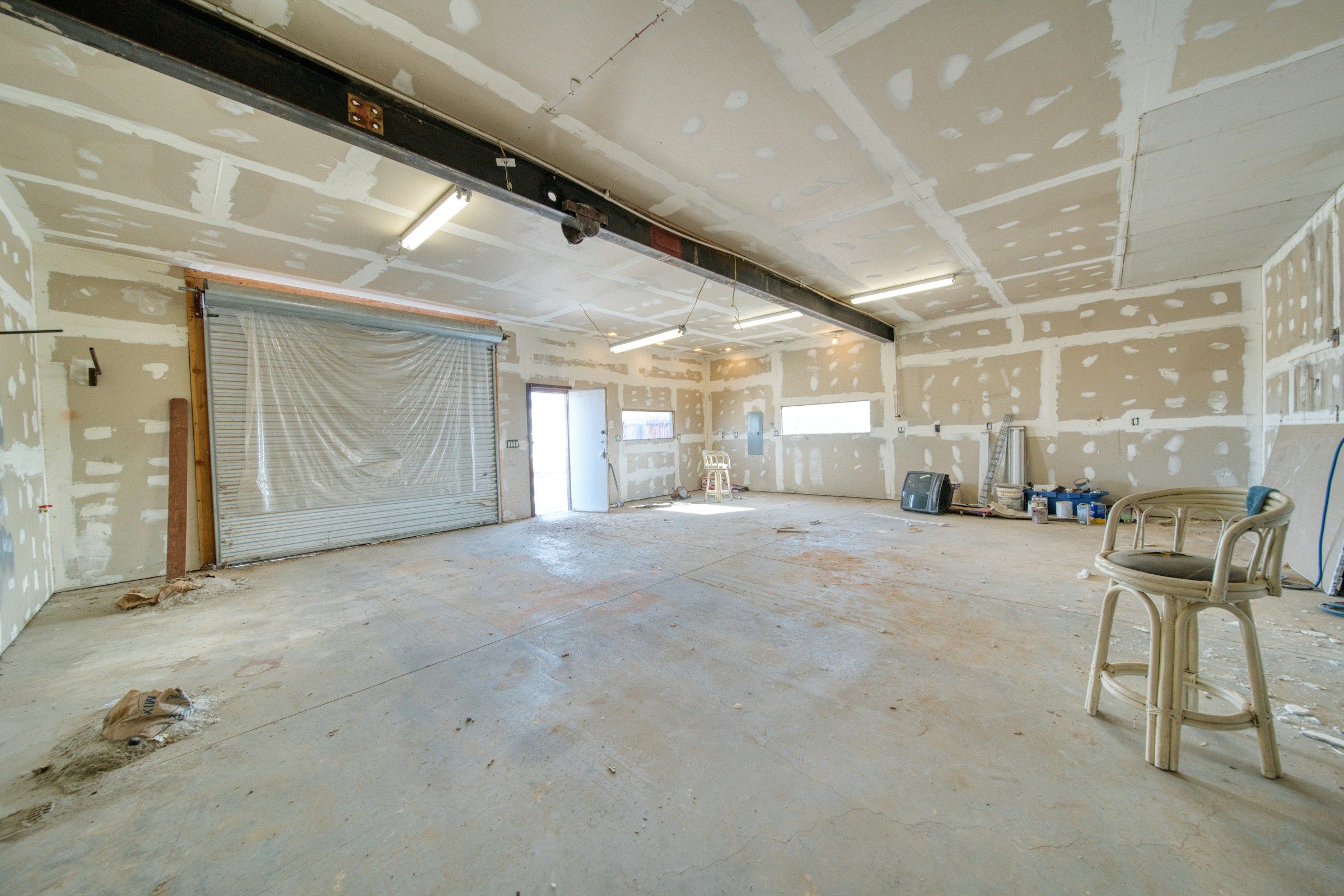 Large room with freshly taped and mudded drywall on the walls and ceiling