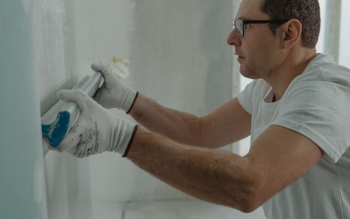 Worker spreading joint compound over a drywall patch