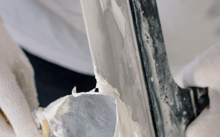 Two putty knives loaded with joint compound