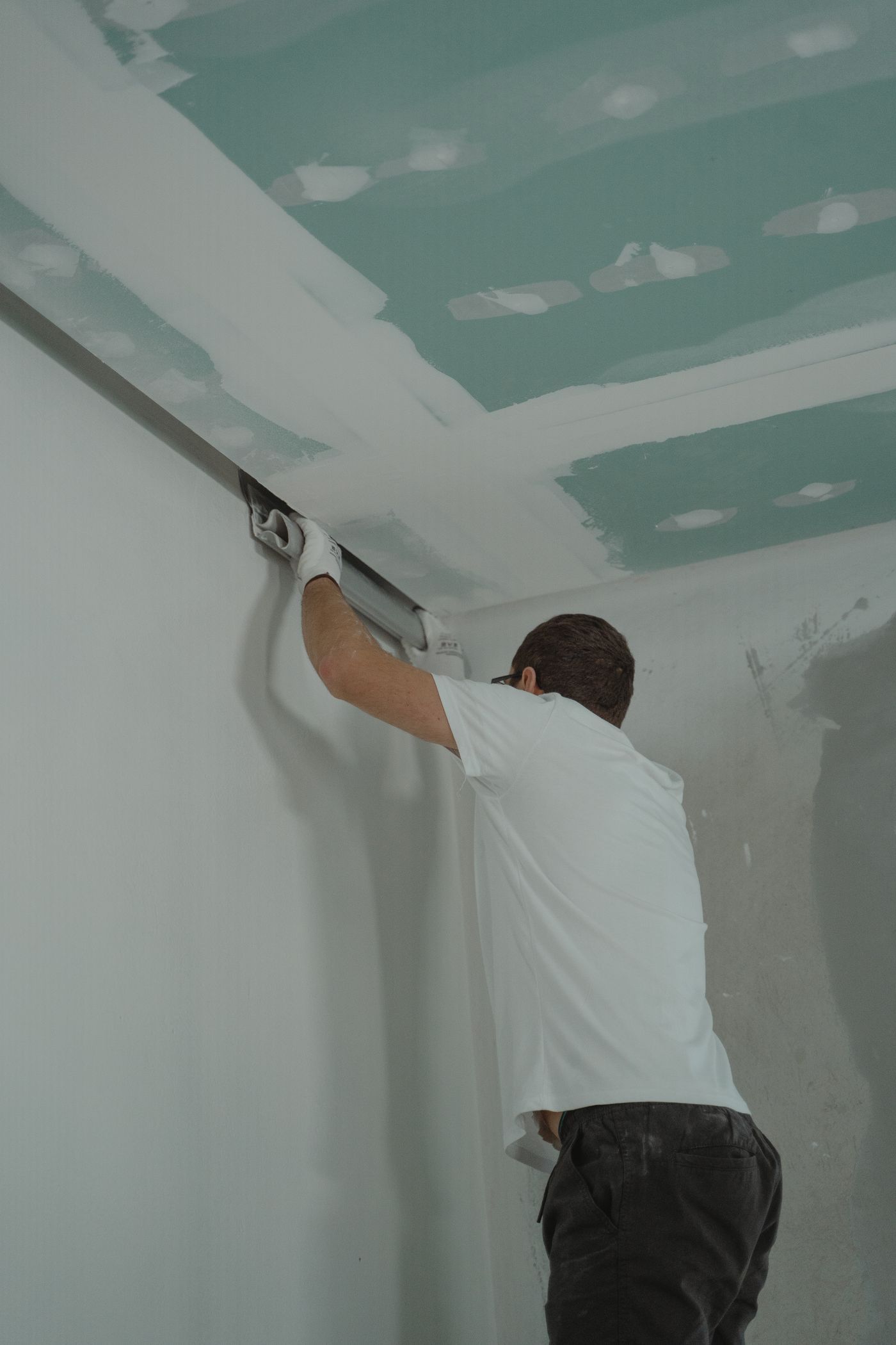 Drywall finisher mudding the seams where the wall meets the ceiling