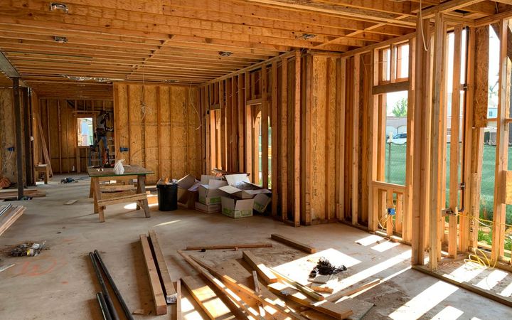 Framed room with open stud walls and ceiling joists, ready for insulation and board