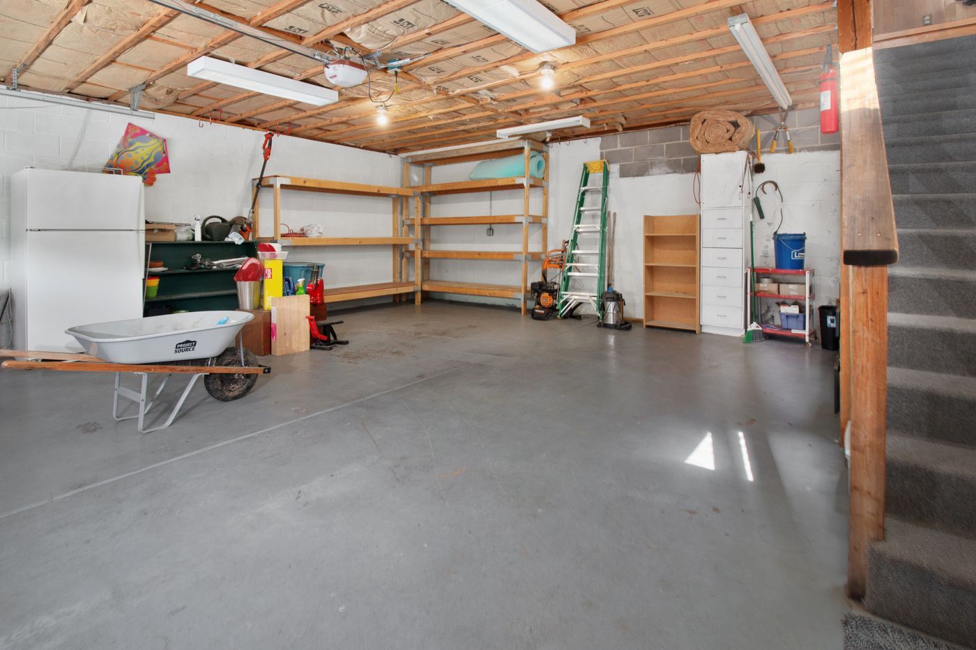 Attached garage interior with shelving and an open ceiling