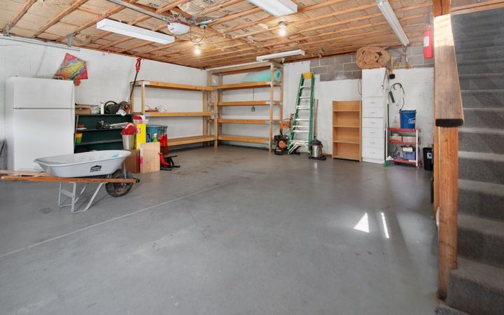 Attached garage interior with shelving and an open ceiling