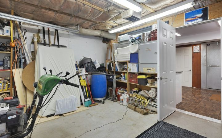 Finished garage with white drywall walls, shelving and a door into the house