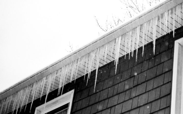 Icicles hanging along the eave of a shingled house