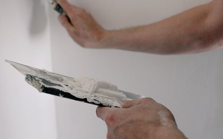 Wide knife pulling a thin coat across a white wall