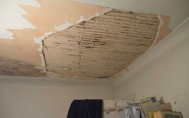 Water-stained plaster ceiling fallen away to expose the wood lath