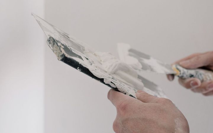 Putty knife spreading compound on a white wall