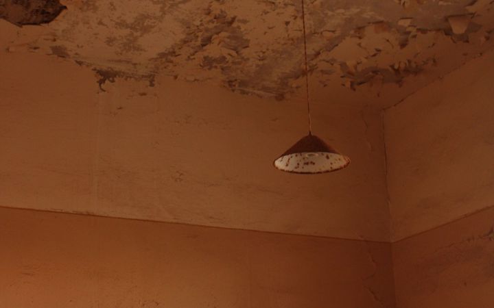 Worn, stained plaster ceiling around an old hanging lamp