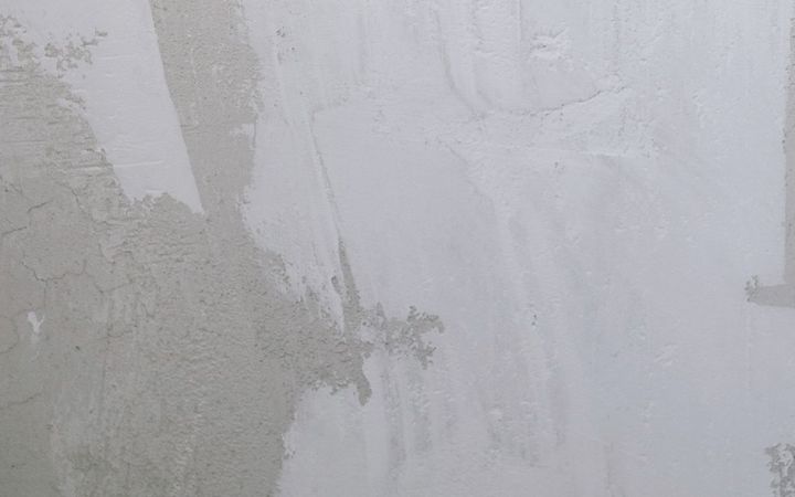 Gray patches of fresh compound drying on a white wall