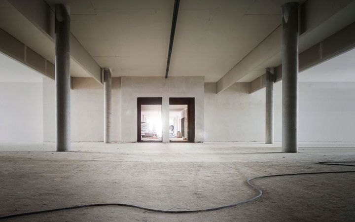 Open industrial shell with concrete columns and new drywall along the walls