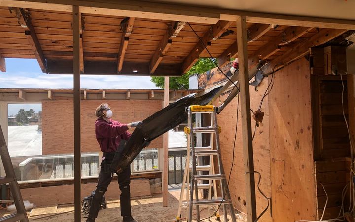 Worker in a respirator pulling down damaged ceiling boards