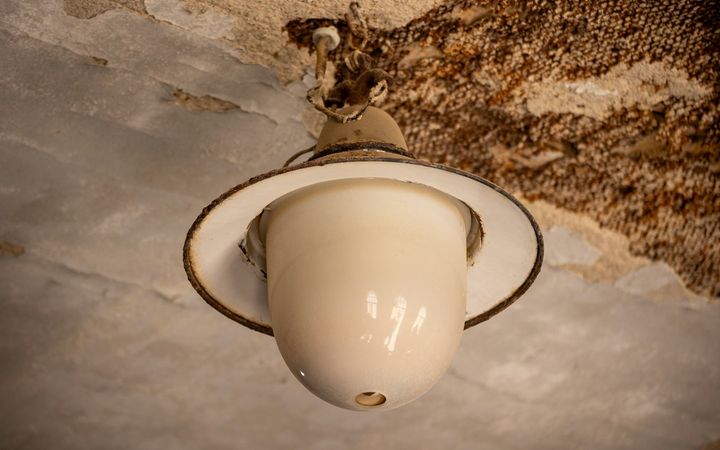 Water-stained, peeling ceiling around an old light fixture